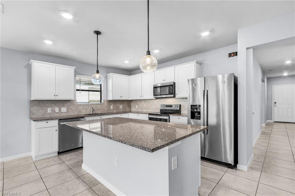 Image 3: Kitchen featuring stainless steel appliances, granite counters, pendant lighting, white cabinetry, and a center island
