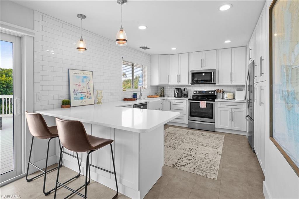 Image 3: Kitchen featuring a peninsula, stainless steel appliances, a breakfast bar, tasteful backsplash, and recessed lighting