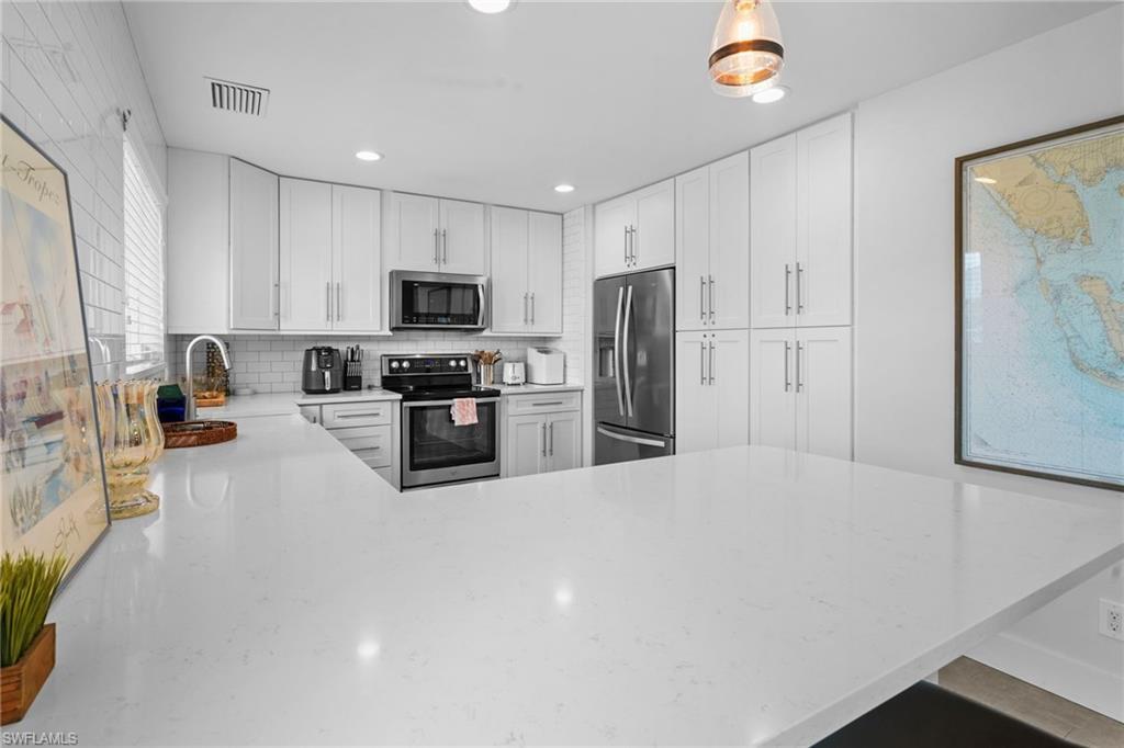 Image 4: Kitchen featuring a peninsula, stainless steel appliances, light stone counters, white cabinetry, and recessed lighting