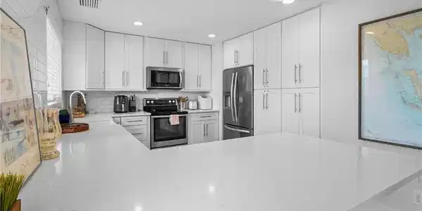 Image 4: Kitchen featuring a peninsula, stainless steel appliances, light stone counters, white cabinetry, and recessed lighting