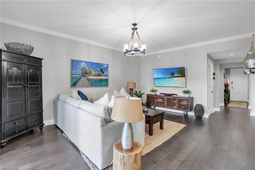 Image 3: Living room with dark wood finished floors, crown molding, and a chandelier