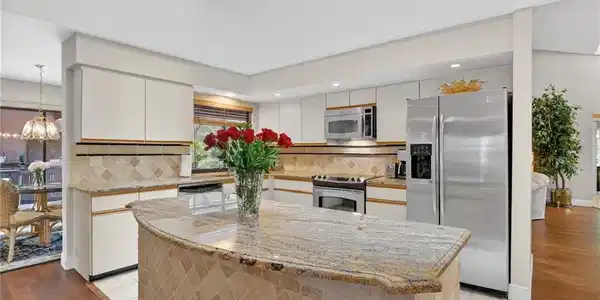 Image 4: Dual tone kitchen with stainless steel appliances, backsplash, light stone countertops, a center island, and a skylight