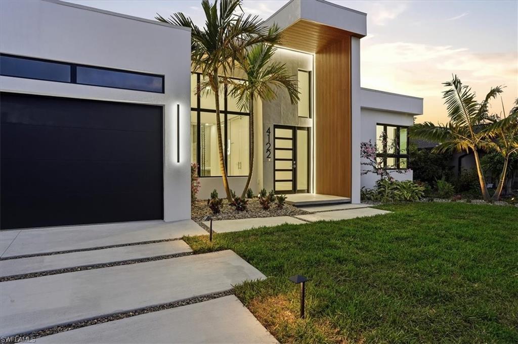 Image 3: Exterior entry at dusk with a lawn, a garage, and stucco siding