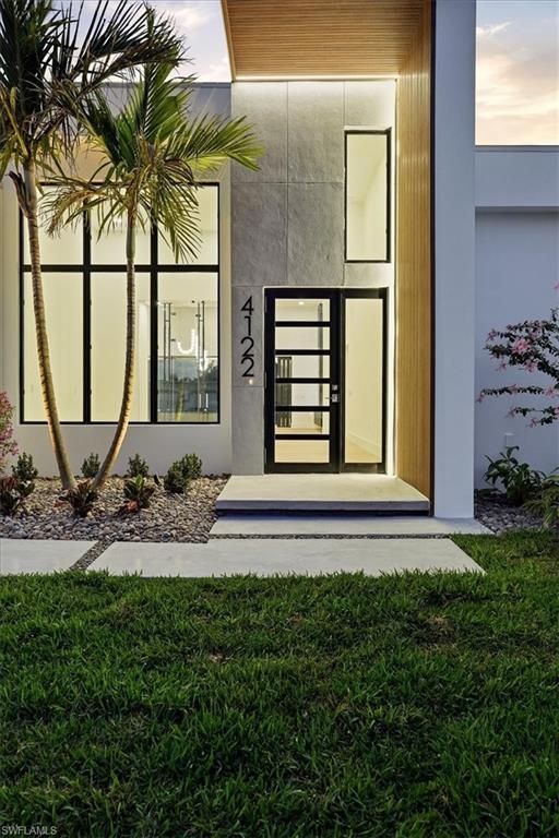 Image 4: Exterior entry at dusk featuring french doors, stucco siding, and a yard