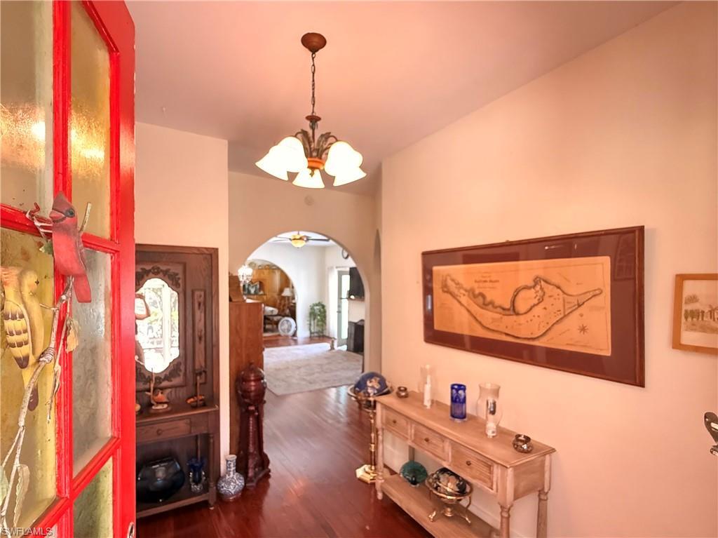 Image 4: Foyer entrance featuring a chandelier, arched walkways, and dark wood-style floors