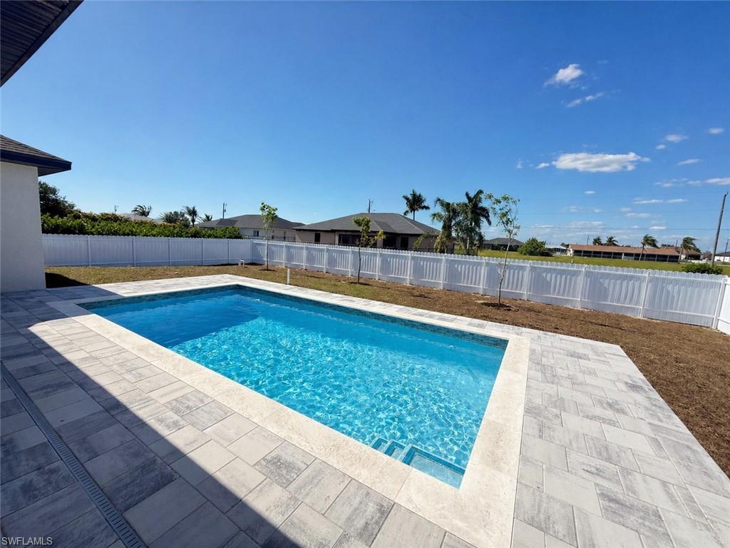 Image 2: Backyard featuring an in-ground swimming pool with steps, surrounded by light-toned paver decking