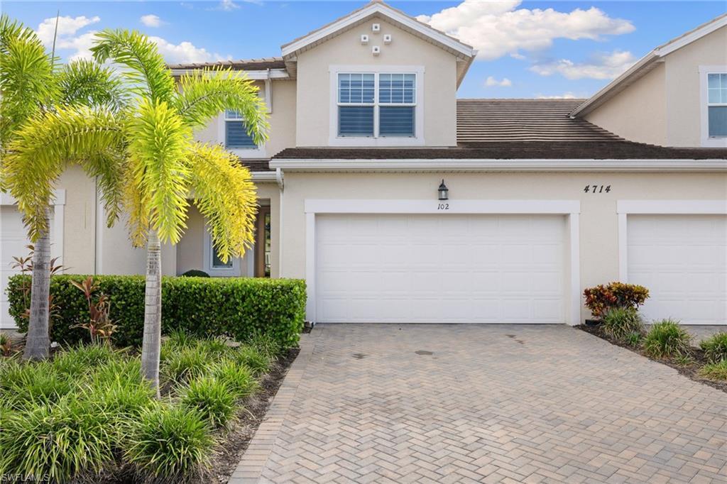 Image 4: Stucco exterior featuring dual garage doors, a paver driveway, and a tile roof