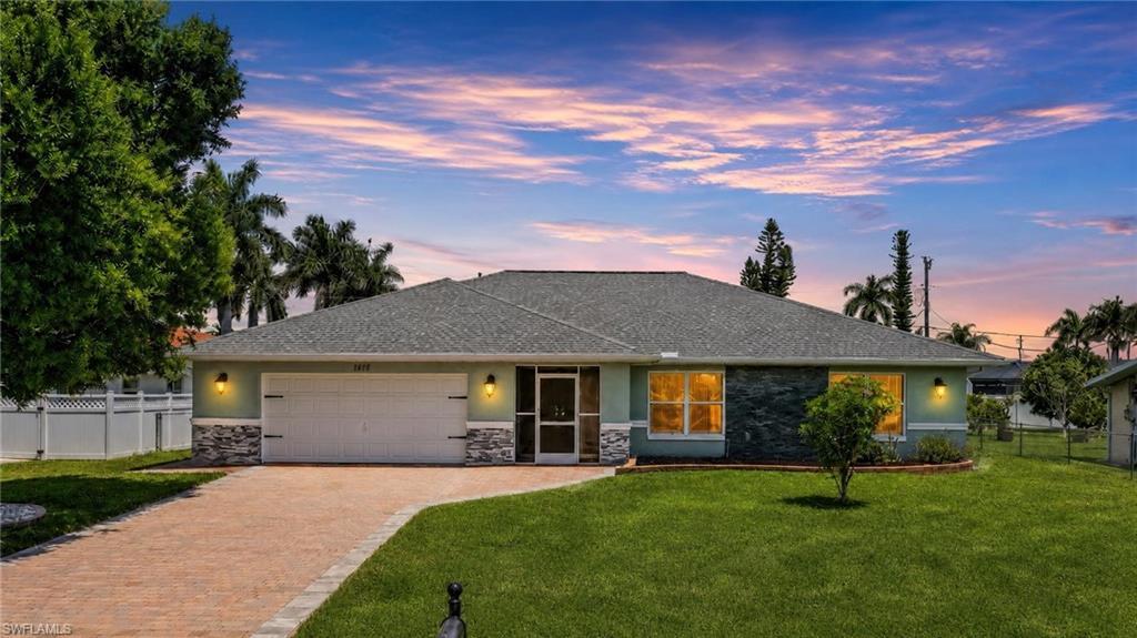 Image 2: Single-story residence featuring a gray shingle roof and a muted green exterior with stone accents