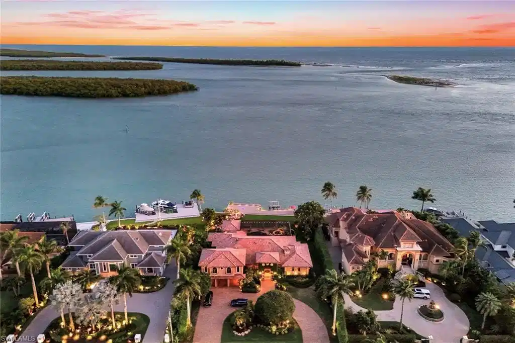 Image 1: Waterfront property featuring a private boat dock, lush tropical landscaping, and a circular driveway
