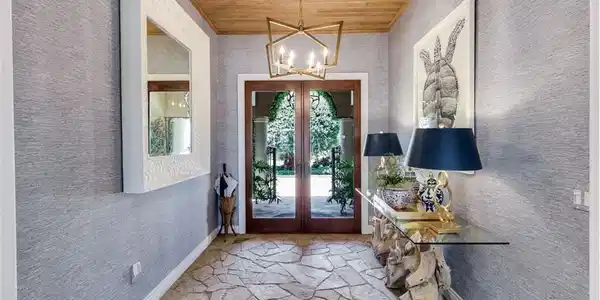 Image 4: Entryway featuring a natural wood plank ceiling, a geometric chandelier, and flagstone flooring
