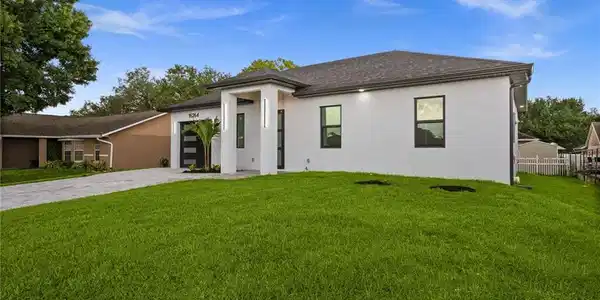 Image 2: Contemporary white stucco exterior with a dark shingle roof