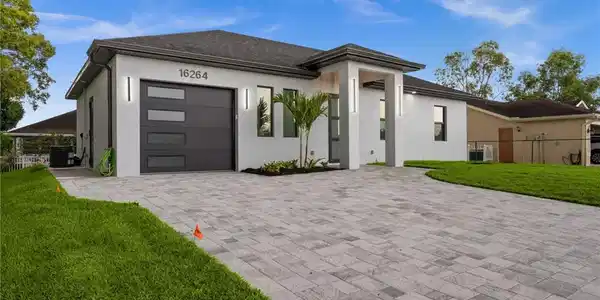 Image 3: Contemporary exterior featuring a paver driveway, an attached garage with translucent paneling, and an inviting covered entry