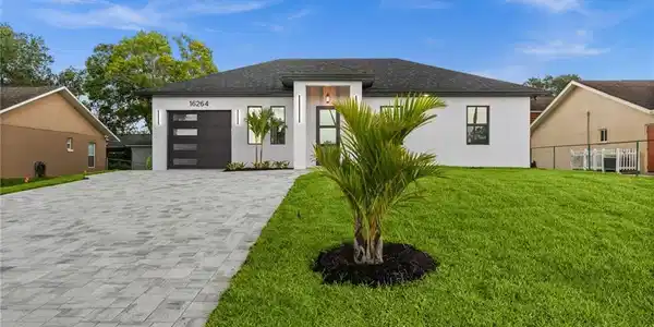 Image 4: Modern single-story residence with a white stucco facade and dark gray roof