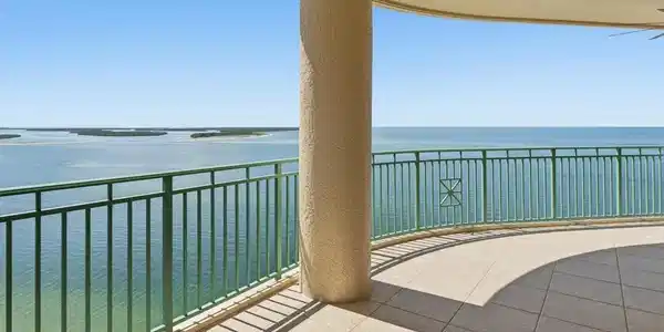 Image 3: Expansive curved balcony featuring a light-toned tile floor and a green metal railing