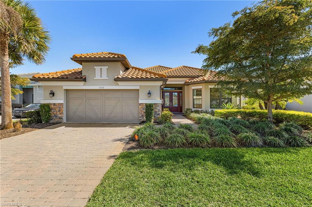 Image 2: Mediterranean / spanish-style house with stone siding, french doors, stucco siding, a front yard, and decorative driveway