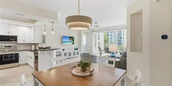Image 3: Open-concept living area with tile flooring and a neutral color palette