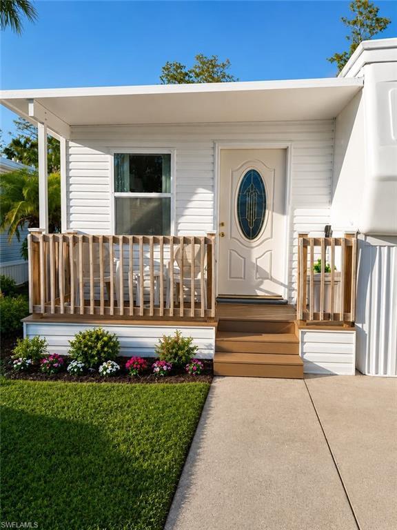 Image 1: Entryway porch featuring a white oval-inset door with patterned glass, composite wood steps, and a white siding exterior