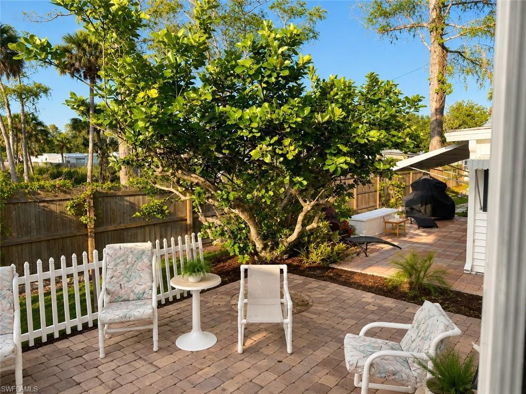 Image 3: Expansive paver patio bordered by a white picket fence and a mature tree