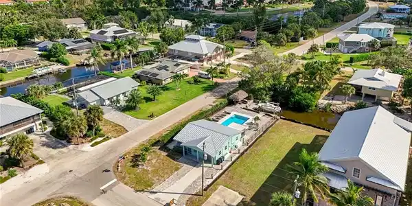 Image 3: Aerial view of residential area with a nearby body of water and a pool area