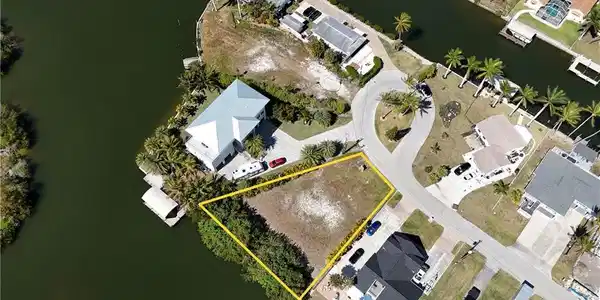 Image 4: Aerial perspective of suburban area featuring a large body of water and property parcel outlined