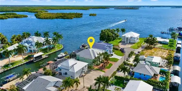 Image 4: Waterfront property with direct water access, boat dock, and multiple mature palm trees - Virtually Edited Image