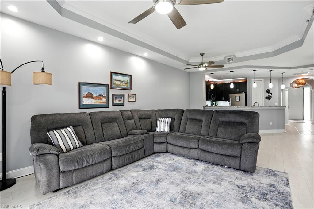 Image 2: Living area with a tray ceiling, ornamental molding, light wood finished floors, recessed lighting, and a ceiling fan