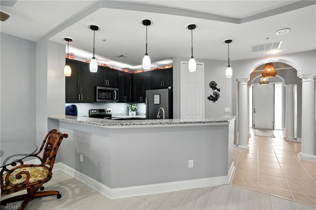 Image 3: Kitchen featuring decorative columns, arched walkways, pendant lighting, a peninsula, and appliances with stainless steel finishes