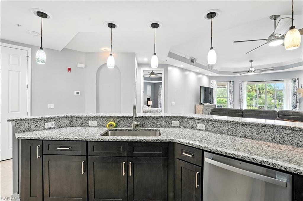 Image 4: Kitchen featuring a raised ceiling, light stone counters, pendant lighting, and dishwasher