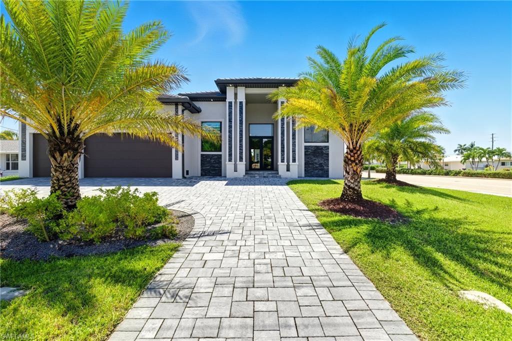 Image 1: View of front of property with decorative driveway, stucco siding, a garage, a front lawn, and a tile roof