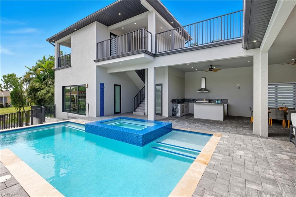 Image 2: Rear view of house featuring a patio, stucco siding, an outdoor kitchen, a ceiling fan, and a pool with connected hot tub