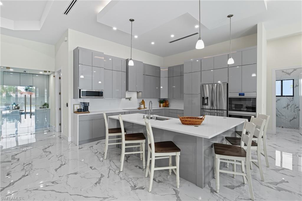 Image 4: Kitchen featuring gray cabinets, pendant lighting, light marble finish floors, modern cabinets, and a breakfast bar