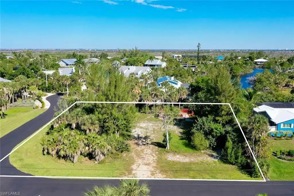 Image 1: Aerial perspective of suburban area with property parcel outlined and a tree filled landscape