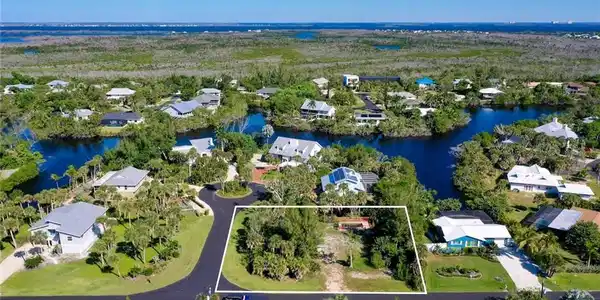 Image 4: Aerial view of residential area with property parcel outlined and a nearby body of water