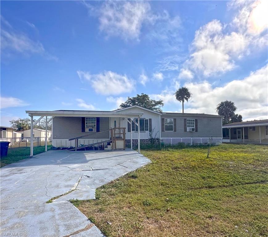 Image 1: Manufactured / mobile home featuring a front lawn, driveway, and a deck