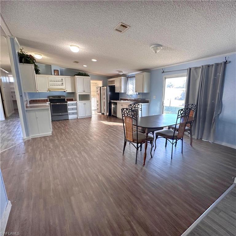 Image 3: Dining area featuring lofted ceiling, dark wood finished floors, and a textured ceiling