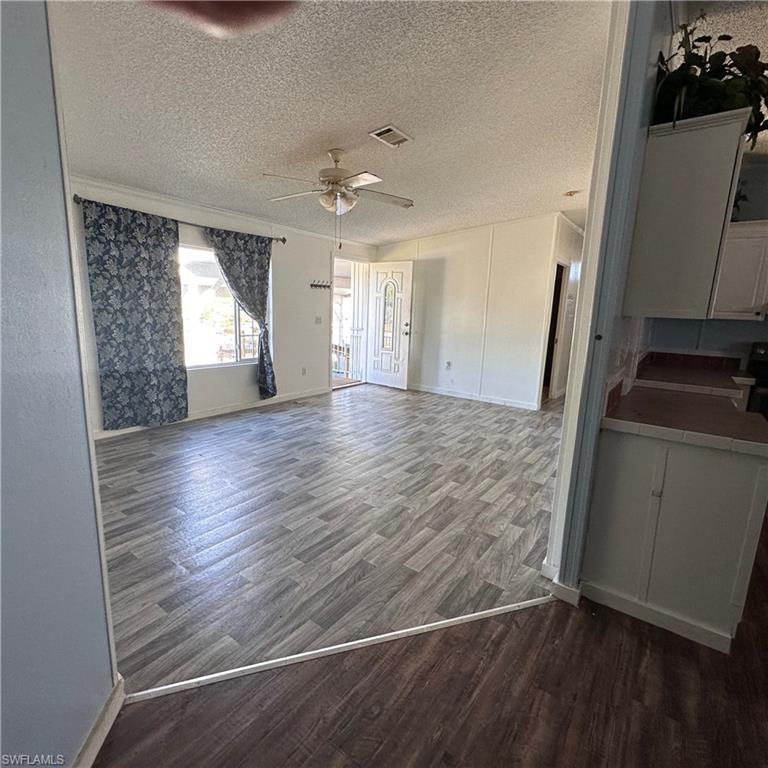 Image 4: Unfurnished living room with dark wood finished floors and a textured ceiling
