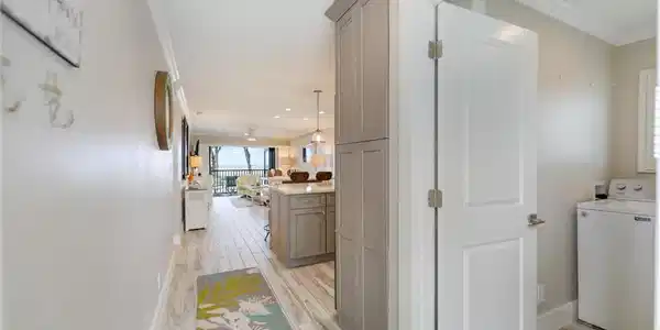 Image 4: Hall with washer / dryer, wood finish floors, and ornamental molding