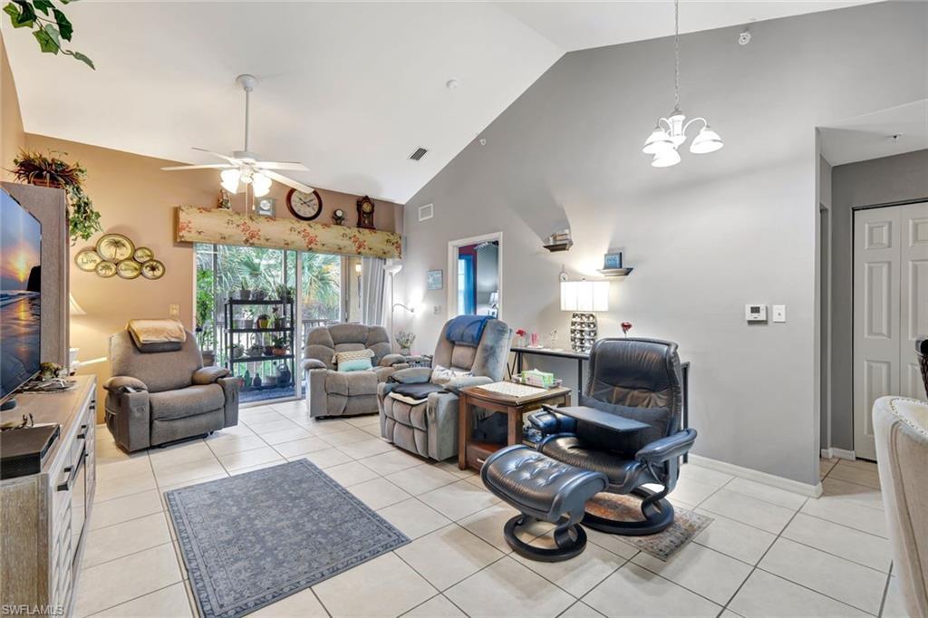 Image 4: Living area with light tile patterned floors, high vaulted ceiling, ceiling fan, and a chandelier