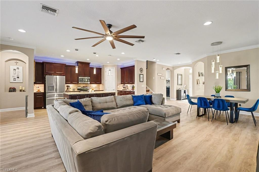 Image 3: Living room featuring arched walkways, crown molding, ceiling fan, light wood finished floors, and recessed lighting