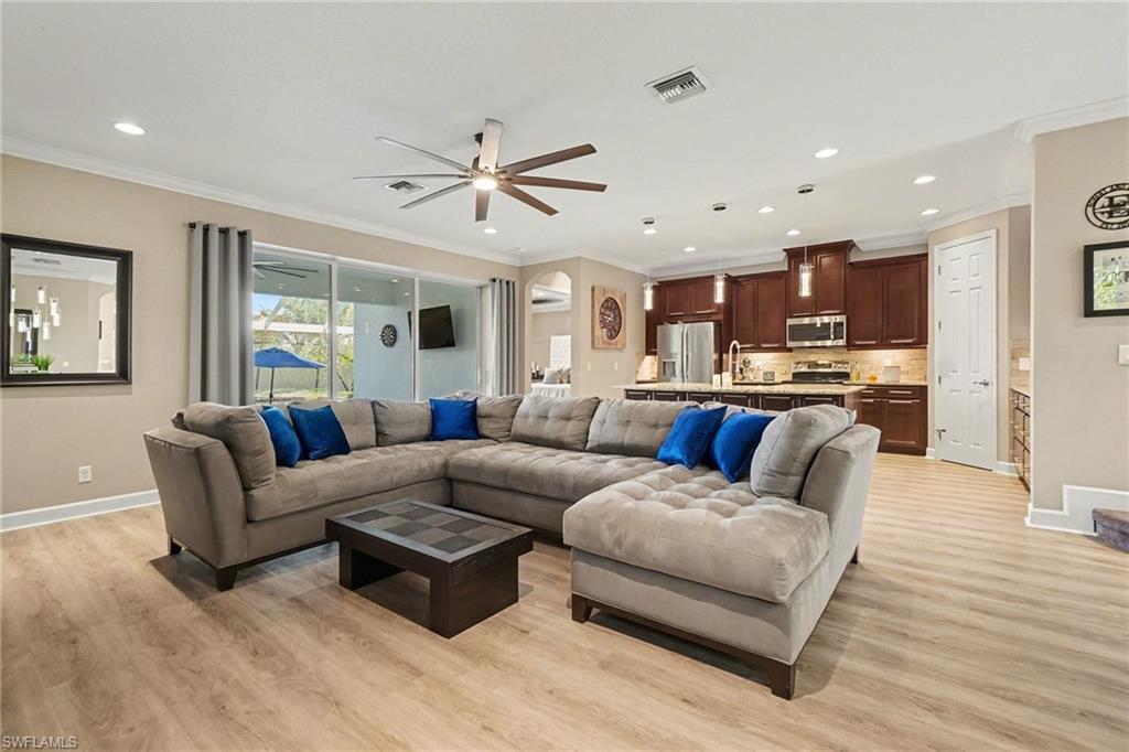 Image 4: Living area with light wood-style floors, a ceiling fan, ornamental molding, and recessed lighting