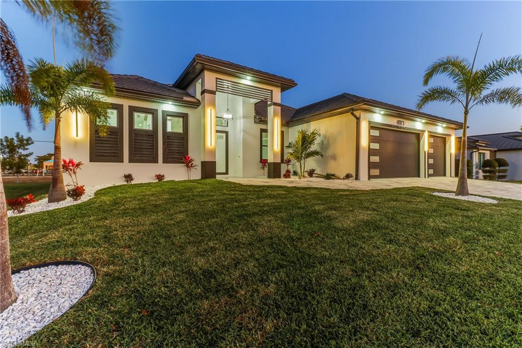 Image 1: View of front of Modern Luxury pool home with a front yard, Concrete block structure, an attached 3 car garage, and paver driveway