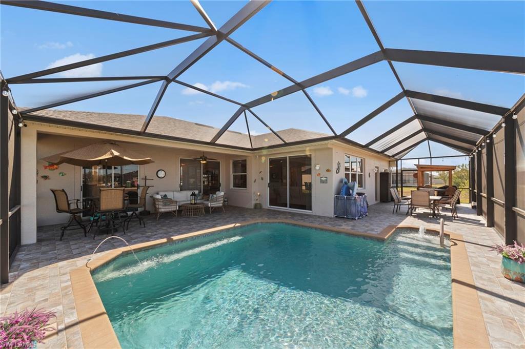 Image 1: Swimming pool featuring an outdoor living / dining area, a sunroom, a patio, and glass enclosure