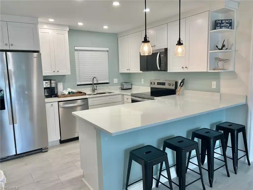 Image 1: Kitchen featuring a breakfast bar, stainless steel appliances, a peninsula, and white cabinets