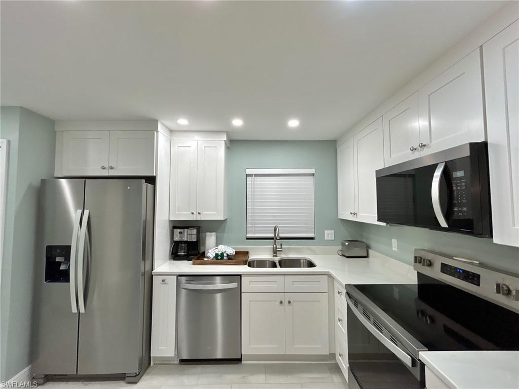 Image 3: Kitchen with stainless steel appliances, white cabinetry, recessed lighting, and light countertops