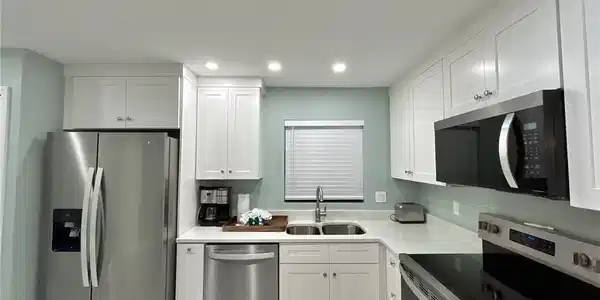 Image 3: Kitchen with stainless steel appliances, white cabinetry, recessed lighting, and light countertops