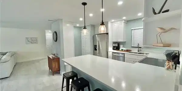 Image 4: Kitchen featuring a kitchen breakfast bar, a peninsula, stainless steel appliances, white cabinetry, and hanging light fixtures