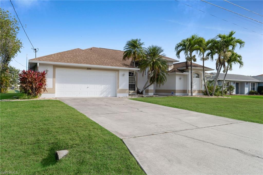 Image 4: Ranch-style house featuring an attached garage, stucco siding, concrete driveway, and a front yard