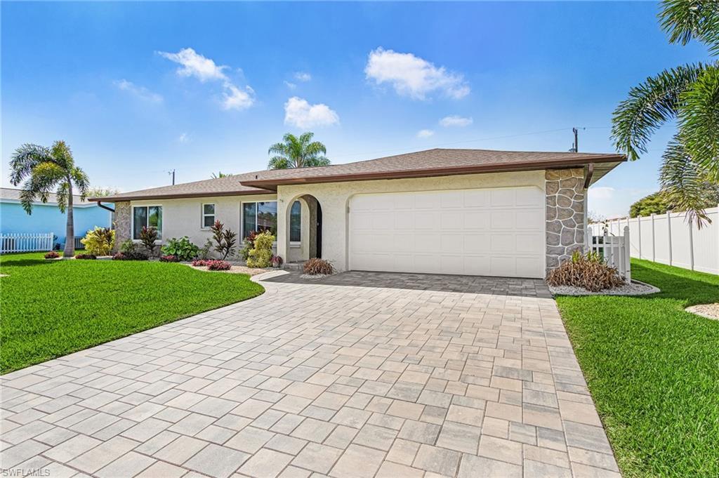Image 1: Ranch-style home with pavered driveway, newly installed hurricane rated impact and automated garage door, stucco sided concrete block home with added stone decor.