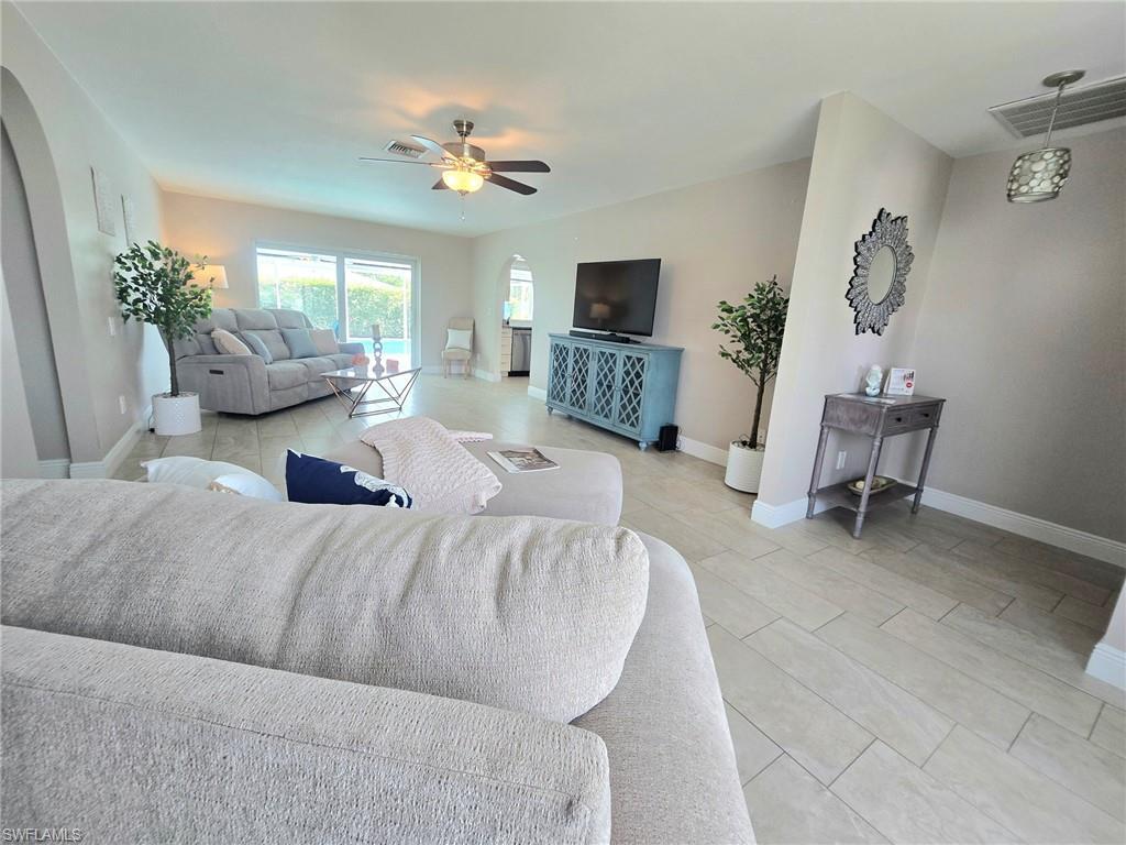 Image 3: Spacious Living room with  plank tile flooring, ceiling fan, nuetral paint, natural light with sliding doors leading to screen enclosed pool area