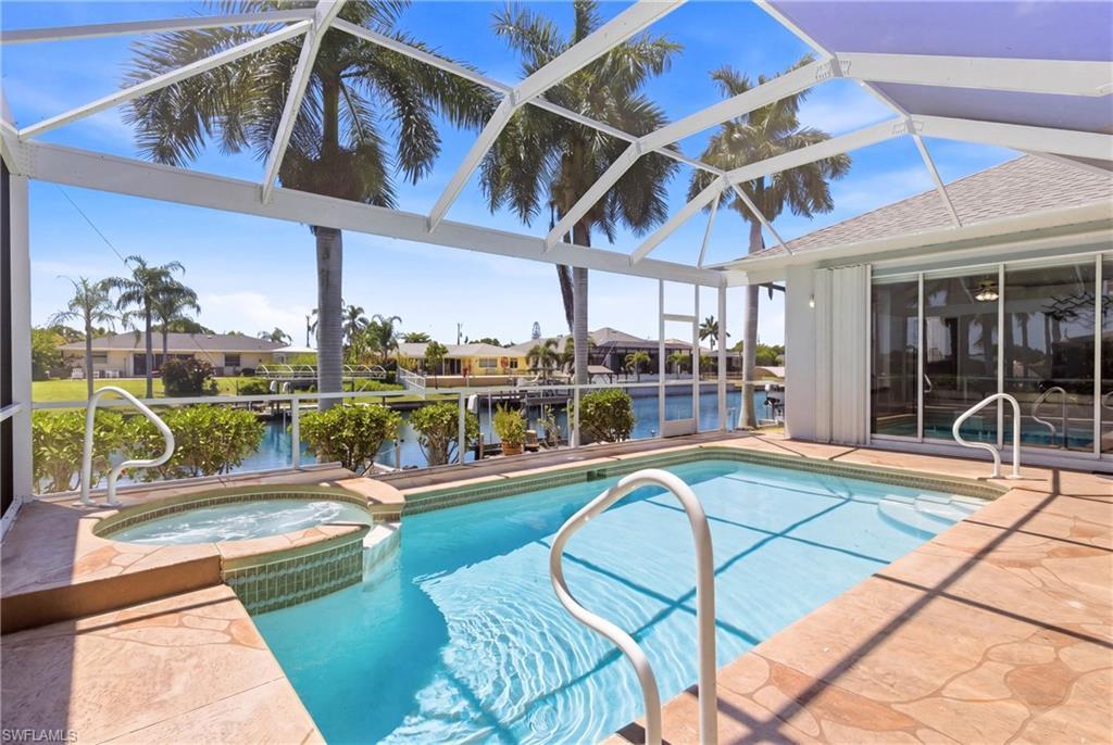 Image 4: The property features a screened-in pool and an integrated hot tub, with a paved surround
